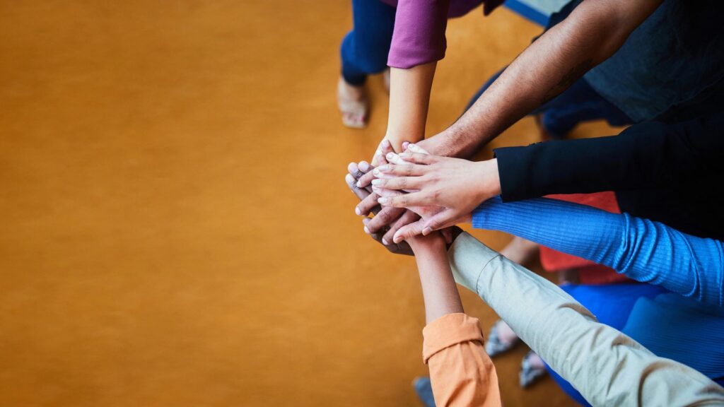 Diverse businesspeople standing in an office with their hands together